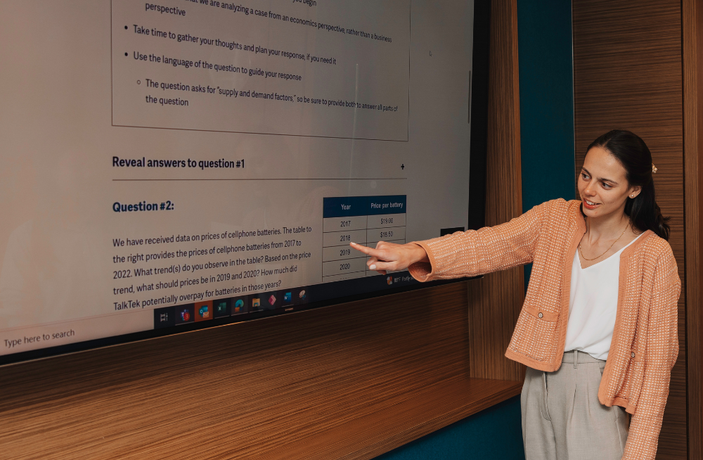 A young woman pointing at a screen containing example Case Interview questions.